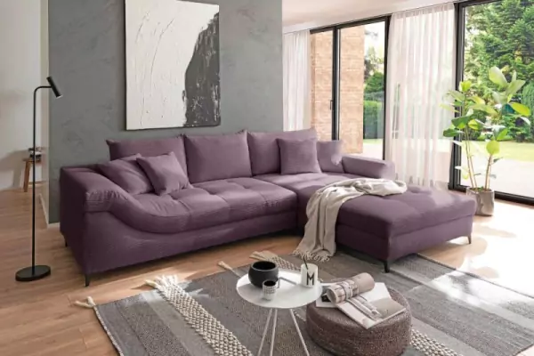 Lila Eckcouch Perry aus Cord mit farblich passenden Sofakissen. Das Sofa steht auf einem schwarzgemusterten Teppich mit einem weißen Couchtisch und einem schwarzen Hocker