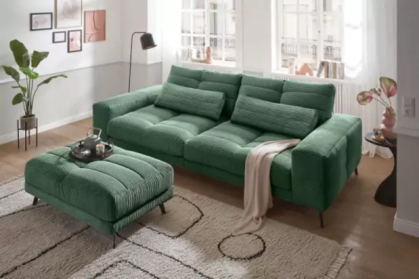 Helmond Cordsofa in Grün 3-Sitzer mit zwei Kissen in Grün. Breitcord. Passender Hocker auf hellbraunem Fransenteppich